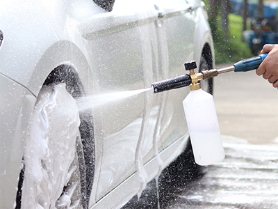 a car completely covered in thick, white 'snow foam' from a high-pressure cannon