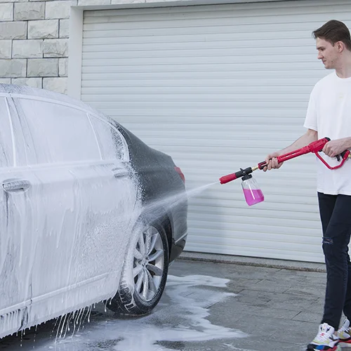 A close-up of a pressure washer foam cannon generating thick, shaving-cream-like foam
